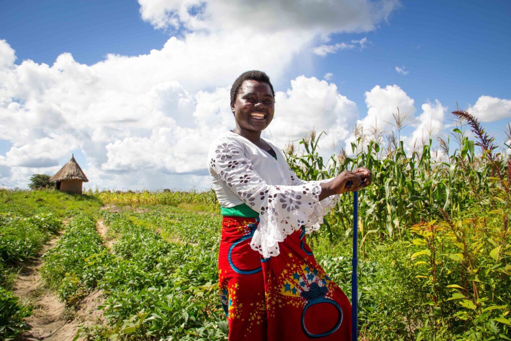 Zambian woman with an agribusiness-supported KickStart MoneyMaker treadle pump for irrigation smallholder farming.